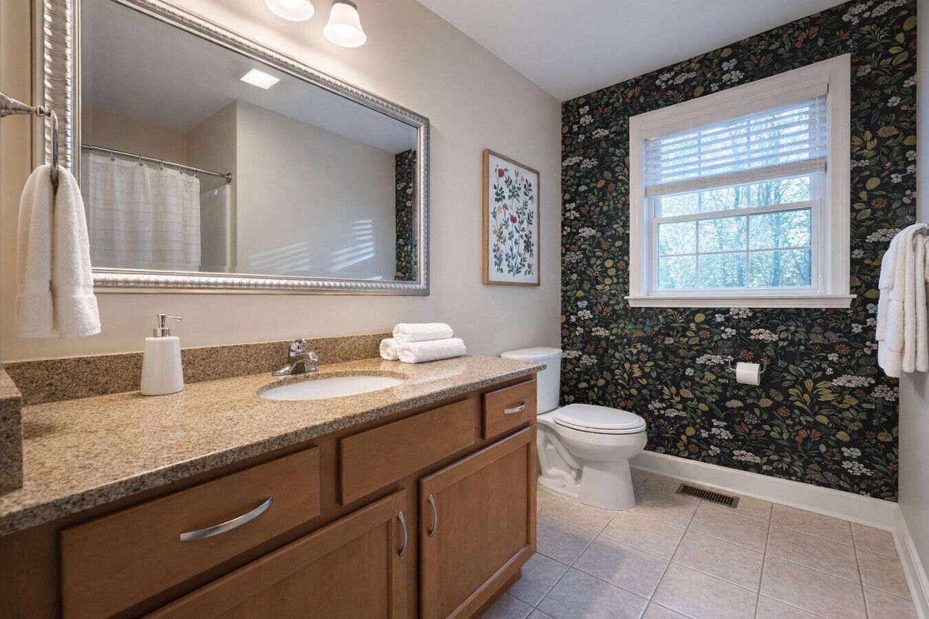A bathroom with a granite countertop, a white sink, a toilet, and a window with blinds.