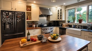 Een moderne keuken met een centraal eiland, roestvrijstalen apparatuur en een raam met planten.