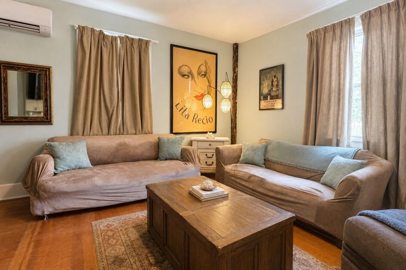 A living room with two sofas, a coffee table, a mirror, and artwork on the walls.