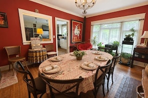 A dining room with a round table set for six, surrounded by wooden chairs.
