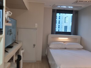 A hotel room with a bed, a desk with a computer, a television, and a window with curtains. - 710ㅣDouble Bed Stay, Just 5 Minutes from Myeongdong Station (Seoul)