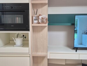 A kitchen with a black oven, a white kettle, and a wooden shelf with a teapot and a small plant. - 710ㅣDouble Bed Stay, Just 5 Minutes from Myeongdong Station (Seoul)
