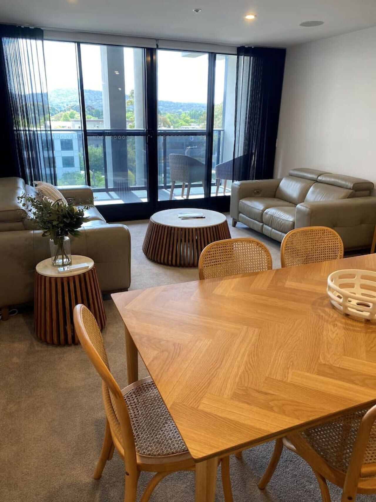 Een moderne woonkamer met een houten eettafel, twee banken en uitzicht op de omgeving.