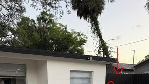 A residential building with a garage door, a white exterior, and a parked white car.