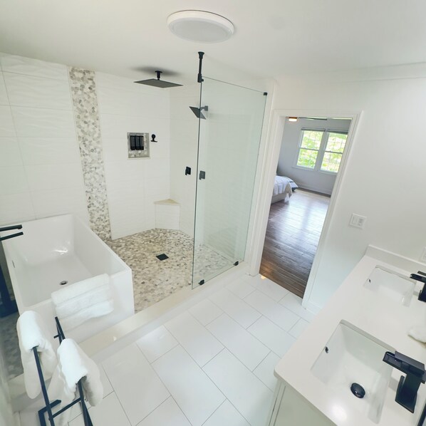 Une salle de bain moderne avec une douche à parois de verre, une baignoire sur pieds et un espace lavabo séparé.