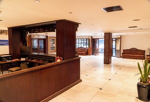 A hotel lobby with a reception desk, seating area, and a large window offering a view. - Belsons TajMahal Hotel (Hyderabad)