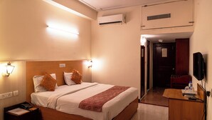 Ein Hotelzimmer mit einem Bett, Nachttischlampen, einem Schreibtisch, einem Stuhl, einer Klimaanlage und einem Fernseher.