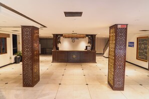 A reception area with a reception desk, a clock, and a 'No Smoking' sign. - Belsons TajMahal Hotel (Hyderabad)