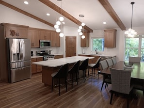 A modern kitchen with wooden cabinets, stainless steel appliances, and a central island with bar stools.