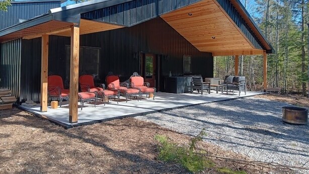 A modern cabin with a covered patio, outdoor seating, and a fire pit. - Secluded Lake Michigan Retreat 4BR/4BA, EV Charging, Near Cave Point (Sturgeon Bay)