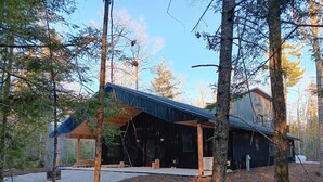 A modern cabin with a covered porch, surrounded by trees. - Secluded Lake Michigan Retreat 4BR/4BA, EV Charging, Near Cave Point (Sturgeon Bay)