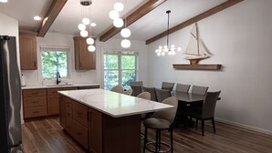 Una cucina moderna con mobili in legno, una grande isola e luci a sospensione.