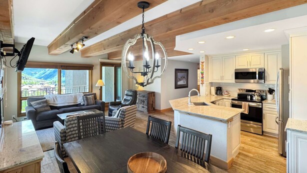 Una cocina moderna con una isla central, vigas de madera y un amplio ventanal con vistas panorámicas.