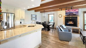 Una cocina moderna con una isla central, un comedor con chimenea y una zona de estar acogedora.