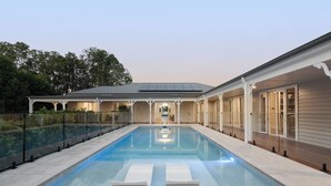 A swimming pool with lounge chairs, a covered patio, and a view of the house.