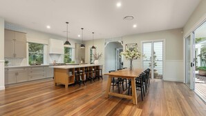 A spacious kitchen with a central island, wooden flooring, and pendant lighting.