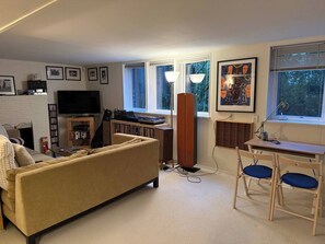 Ein Wohnzimmer mit einer Couch, einem Fernseher, einem Kamin und einem Essbereich mit Stühlen.