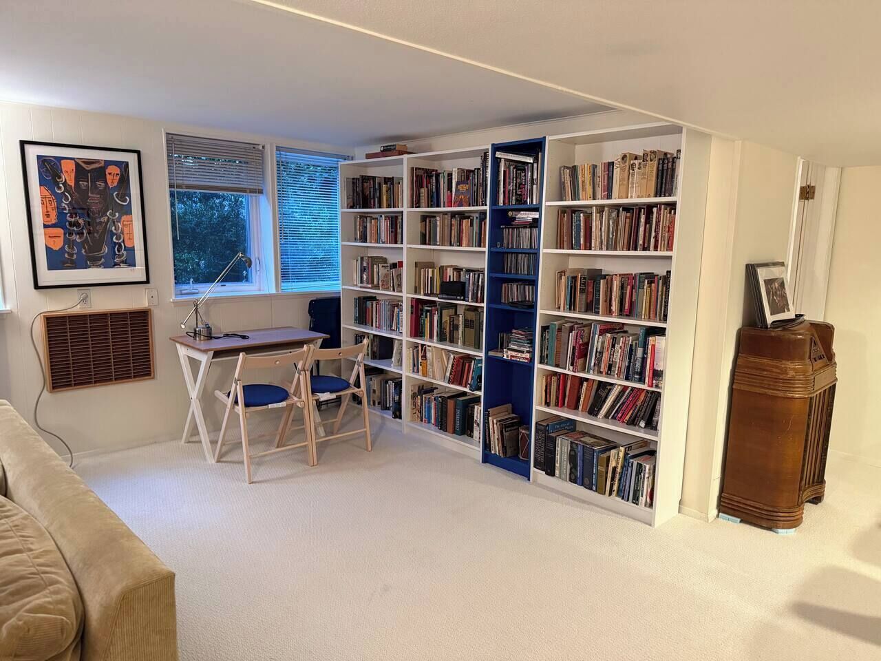 Quarto com escrivaninha, cadeira, estante e radiador.