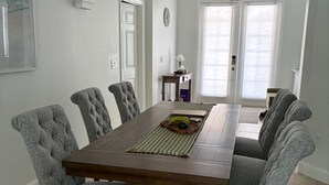 Ein Esszimmer mit einem rechteckigen Tisch, gepolsterten Stühlen und einer Kristallleuchter.