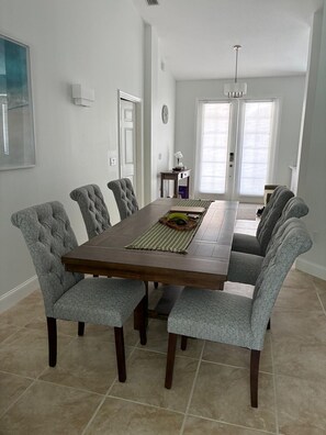 A dining room with a rectangular table, tufted chairs, and a chandelier. - Privacy, pool and close to Manasota Beach (Englewood)