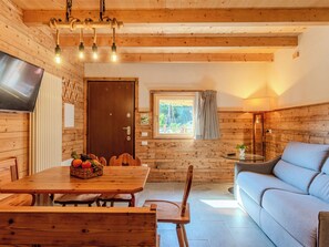 Un intérieur chaleureux, avec des murs en bois, une table à manger, des chaises, un canapé et un téléviseur.