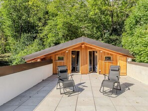 A wooden cabin with a sloped roof, two lounge chairs, and a patio area. - Apartment Olivo by Interhome (Sorico Albonico)