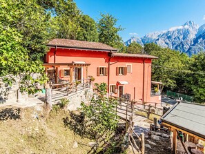A red two-story house with a stone staircase, wooden fence, and a view of snow-capped mountains. - La Palma by Interhome (Sorico Albonico)