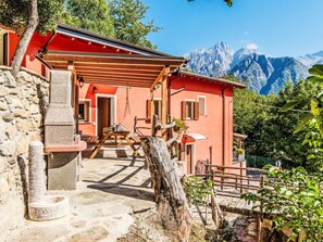 Un edificio rojo con una pared de piedra, una mesa de madera y un banco.