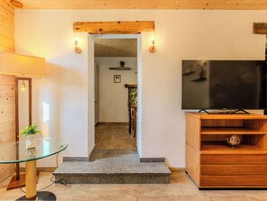 Una sala de estar con una mesa de vidrio, un mueble bajo para televisión de madera y una escalera que lleva a otra habitación.
