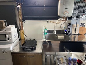 Eine Küche mit Mikrowelle, Toaster, Wasserkocher, Spüle und diversen Küchenutensilien.