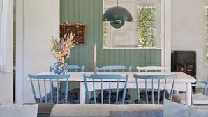 A dining area with a table, chairs, a vase with flowers, a candle, a wall-mounted shelf, and a fireplace. - 4 Star Holiday Home in Spottrup (Spøttrup)