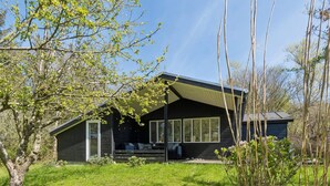 A cabin with a porch, large windows, and a sloped roof. - 4 Star Holiday Home in Spottrup (Spøttrup)