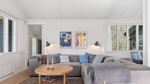 A cozy living room with a grey sofa, a round coffee table, and two wall-mounted lamps. - 4 Star Holiday Home in Spottrup (Spøttrup)
