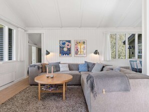 Ein gemütliches Wohnzimmer mit einem grauen Sofa, einem runden Couchtisch und zwei Wandleuchten.