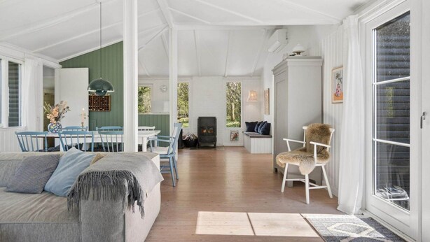 A spacious living area with a sofa, dining table, chairs, and a fireplace. - 4 Star Holiday Home in Spottrup (Spøttrup)