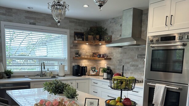 Una cucina moderna con isola in marmo, elettrodomestici in acciaio inossidabile e un lampadario.