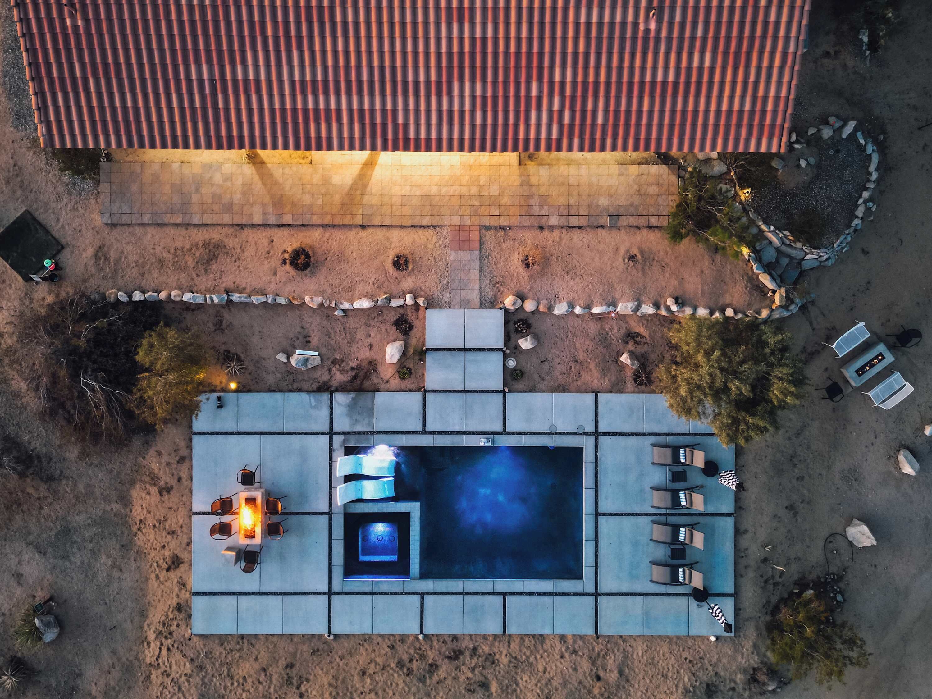 An aerial view of a rooftop pool area with seating and a fire feature.