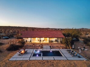A house with a red-tiled roof, a swimming pool, and outdoor seating.