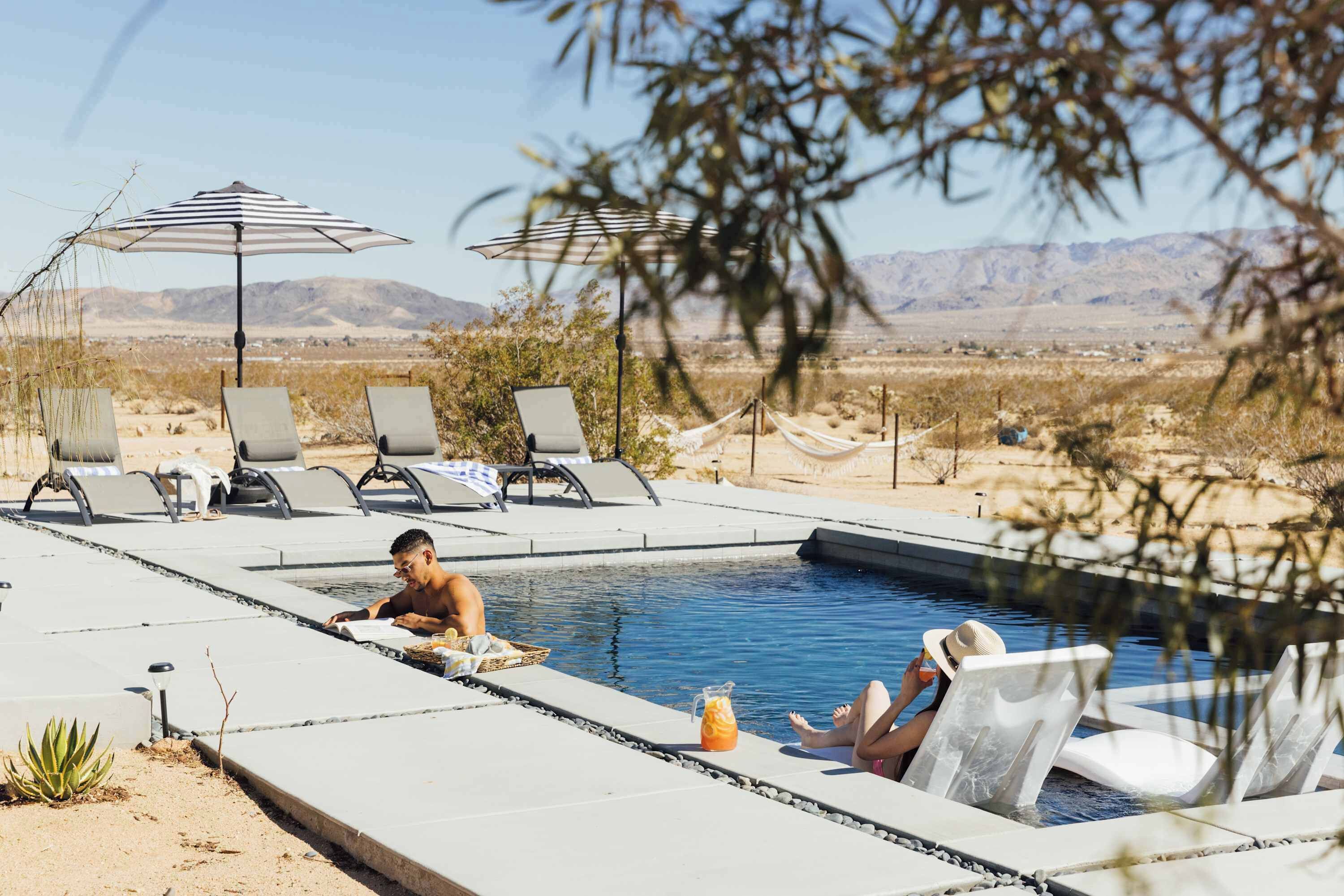 Ein Poolbereich mit Liegestühlen, einer Hängematte und Bergblick.