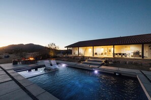 A swimming pool with lounge chairs, a fire pit, and a building with outdoor seating.