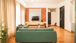 Una sala de estar moderna con un televisor de pantalla plana, una pared de acento de madera y un sofá verde.