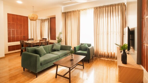 Una sala de estar con un sofá, una mesa de centro, una mesa de comedor con sillas, un televisor y un ventilador de techo.
