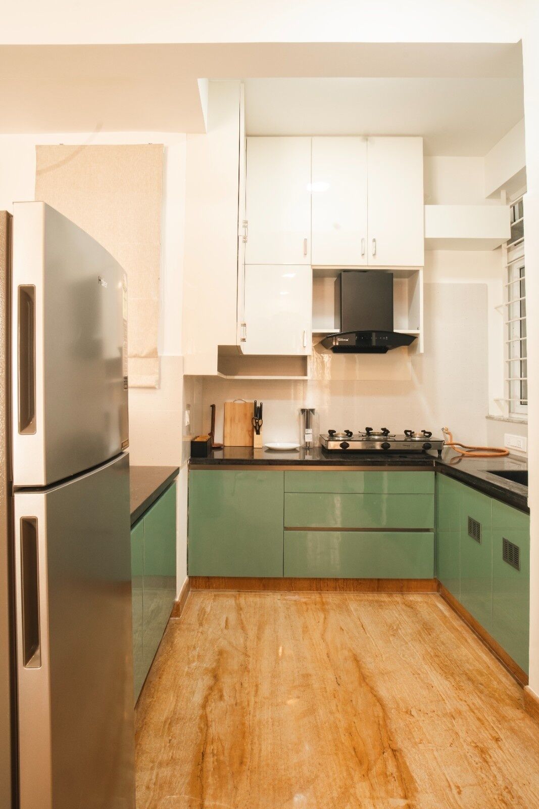 A compact kitchen with a refrigerator, stove, and white cabinets.
