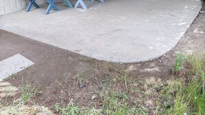 Un patio couvert avec une table et des bancs, une porte-fenêtre coulissante et un mur en briques.