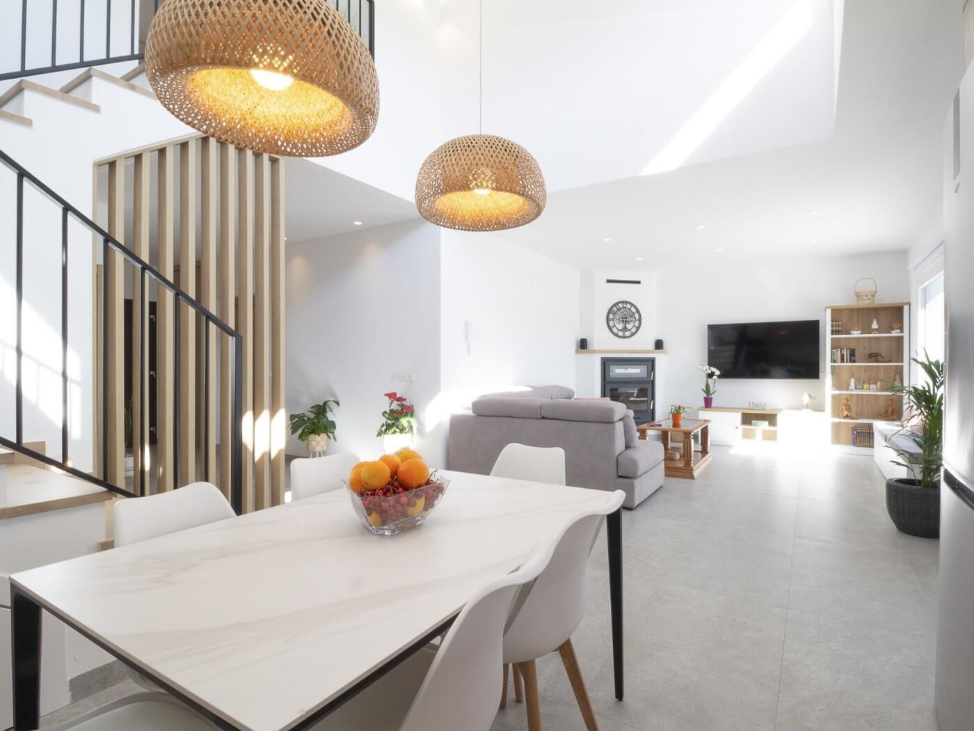 Ein modernes Wohnzimmer mit Essbereich, einer Treppe und einem an der Wand befestigten Fernseher.