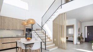 Eine moderne Küche mit Essbereich, einer Treppe und einem Wohnbereich mit Sofa und Pflanze.