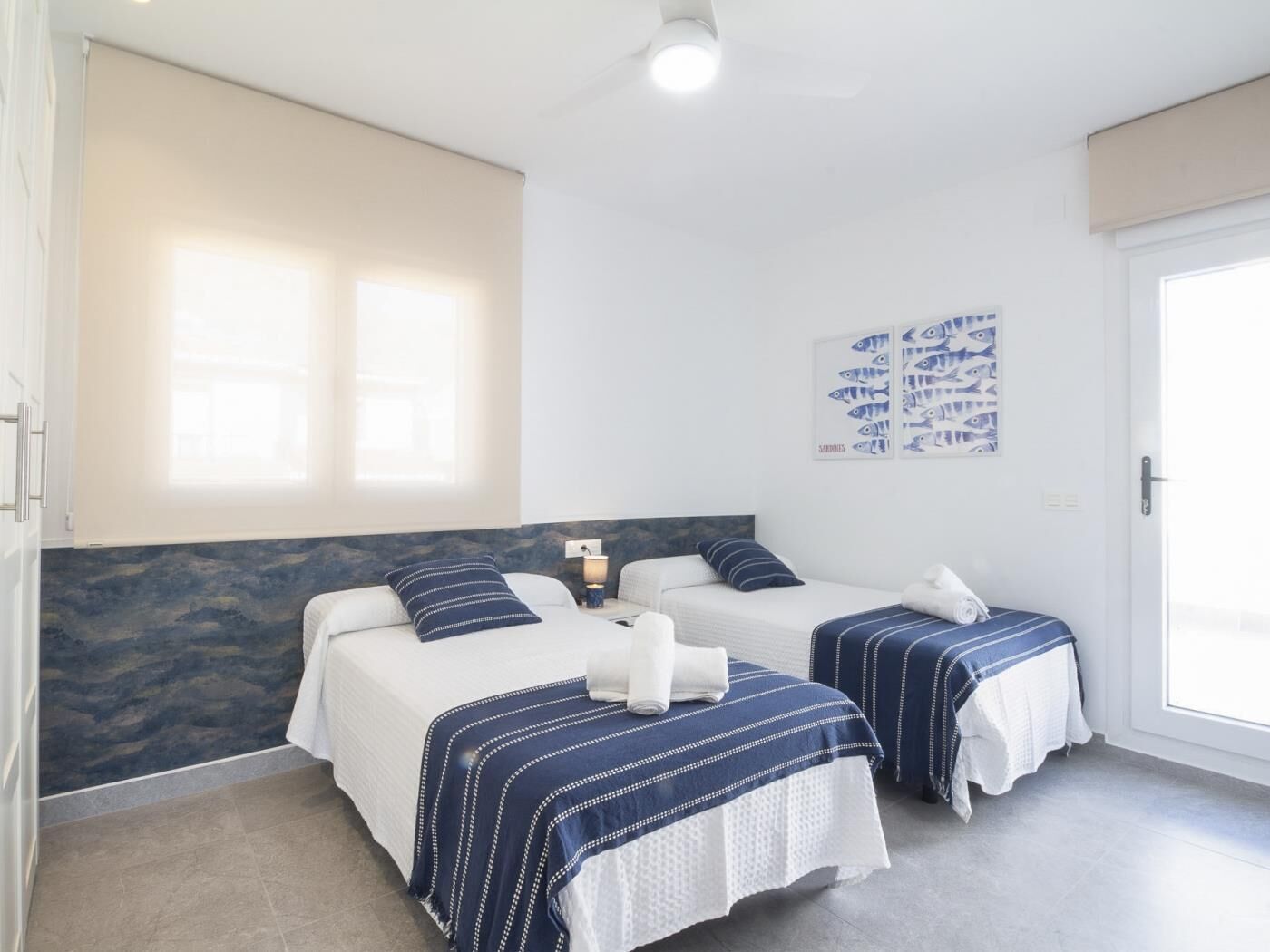 Une chambre d’hôtel avec deux lits, une fenêtre et des œuvres d’art au mur.
