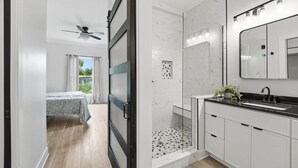Un baño moderno con ducha, lavamanos y un espejo grande.