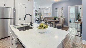 Une cuisine moderne dotée d’un îlot central, d’appareils électroménagers en acier inoxydable et d’un coin repas avec une table et des chaises.
