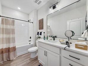 A modern bathroom with a bathtub, toilet, and vanity with a mirror.